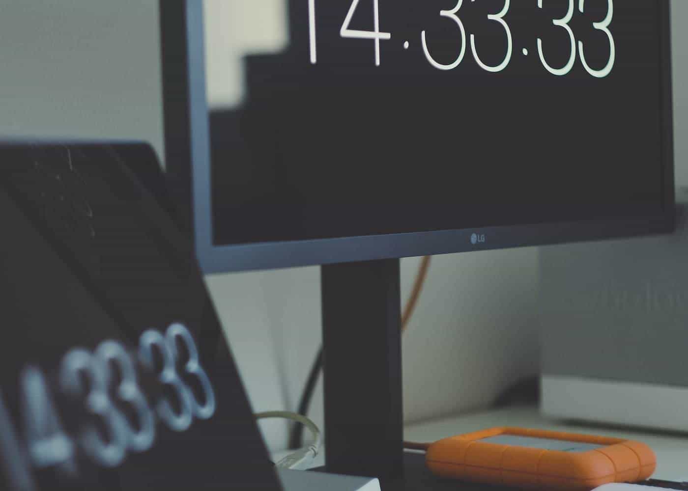 A modern office with computer screens and a digital clock display