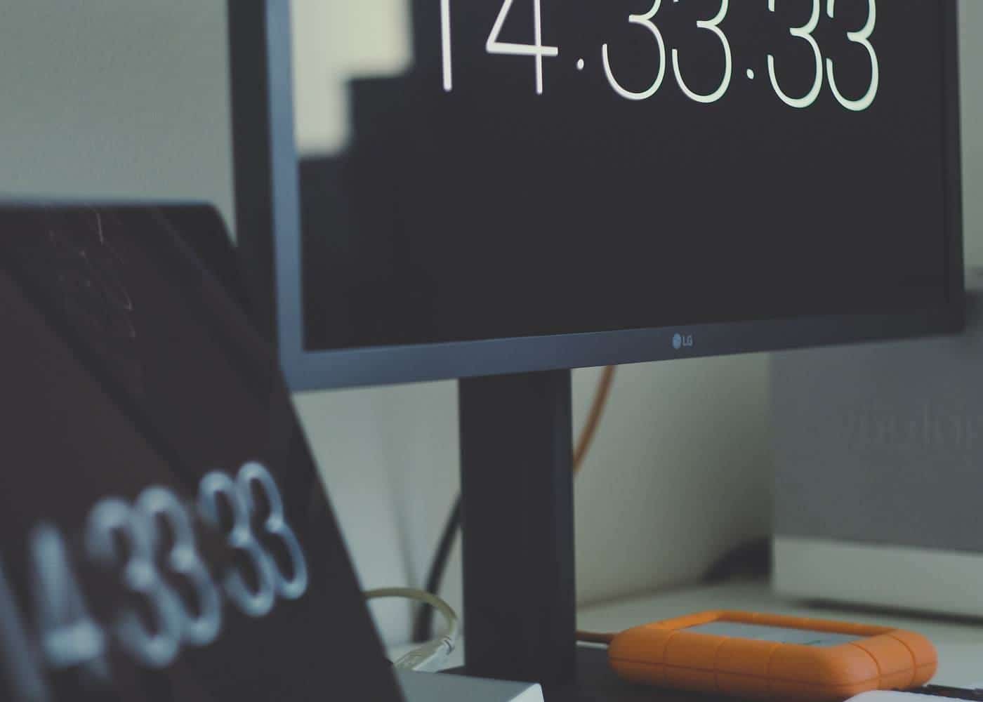 A modern office with computer screens and a digital clock display