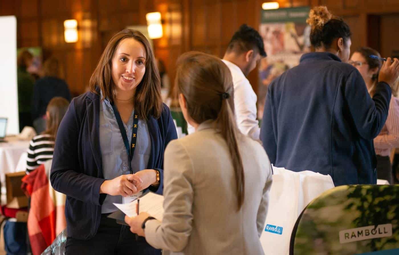 Two women talking at a university careers fair stall