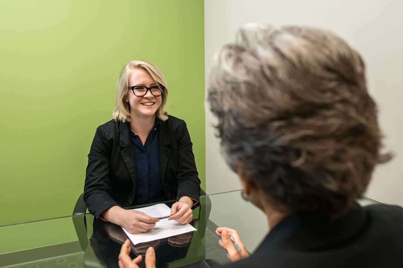 A woman smiling during a job interview across a table from an interviewer