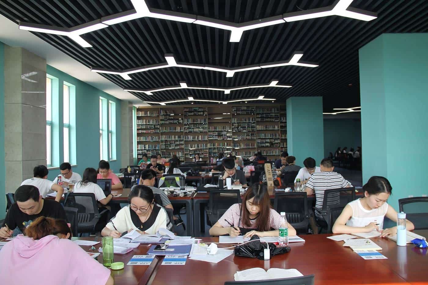 Students studying at long tables in a large university library